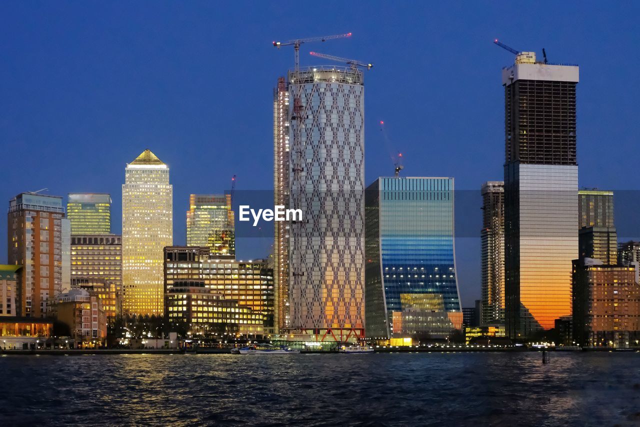 Modern high-rise buildings in city during blue hour at waterfront. 