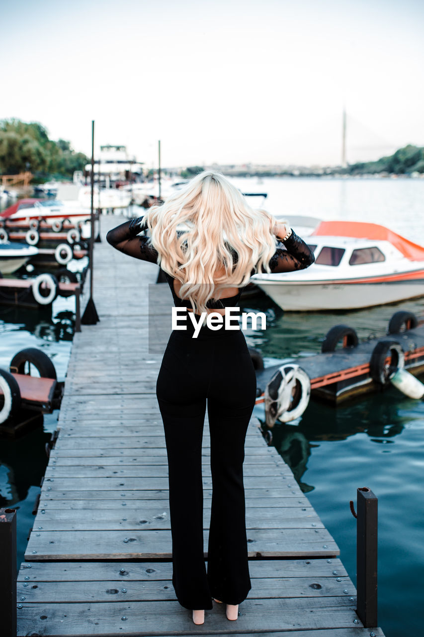 WOMAN STANDING ON PIER OVER LAKE