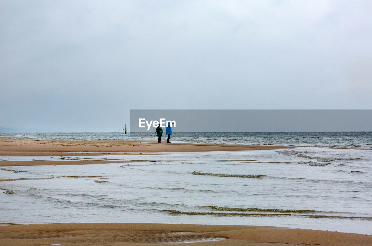 People standing at beach against sky