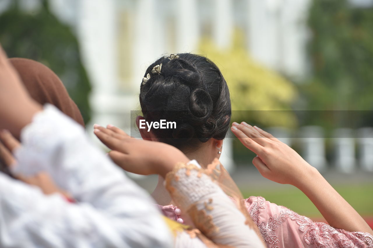 Rear view of woman saluting