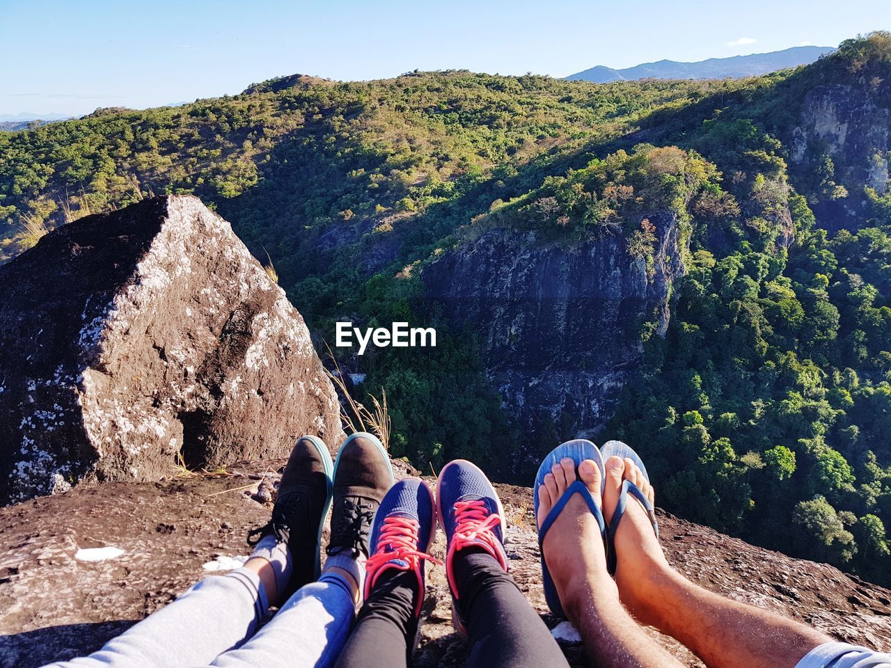 Low section of friends on cliff against mountains