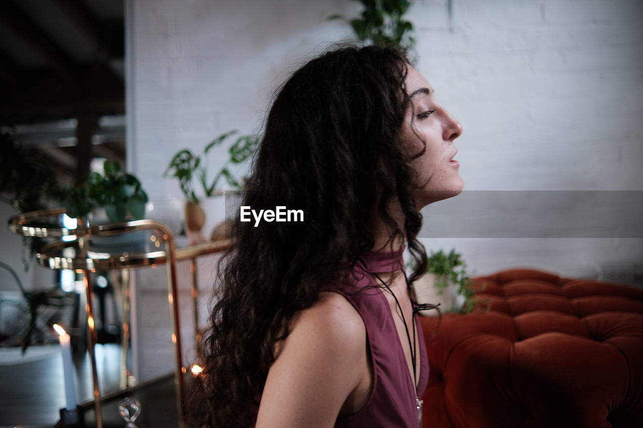 Young woman looking away while sitting at in a beautiful location indoors, spiritual 