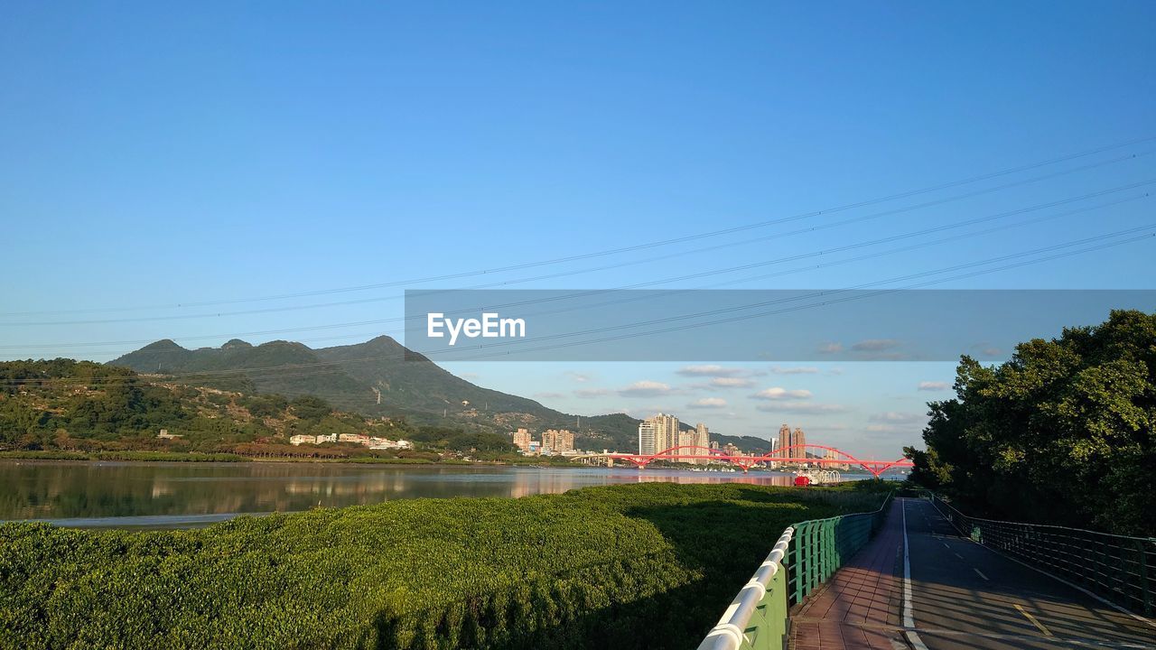 sky, nature, plant, architecture, water, blue, hill, landscape, tree, environment, morning, cable, built structure, beauty in nature, electricity, no people, rural area, scenics - nature, clear sky, land, outdoors, day, reflection, horizon, river, tranquility, transportation, travel destinations, cloud, flower, building, travel, city, growth, technology, rural scene, agriculture, building exterior, tranquil scene