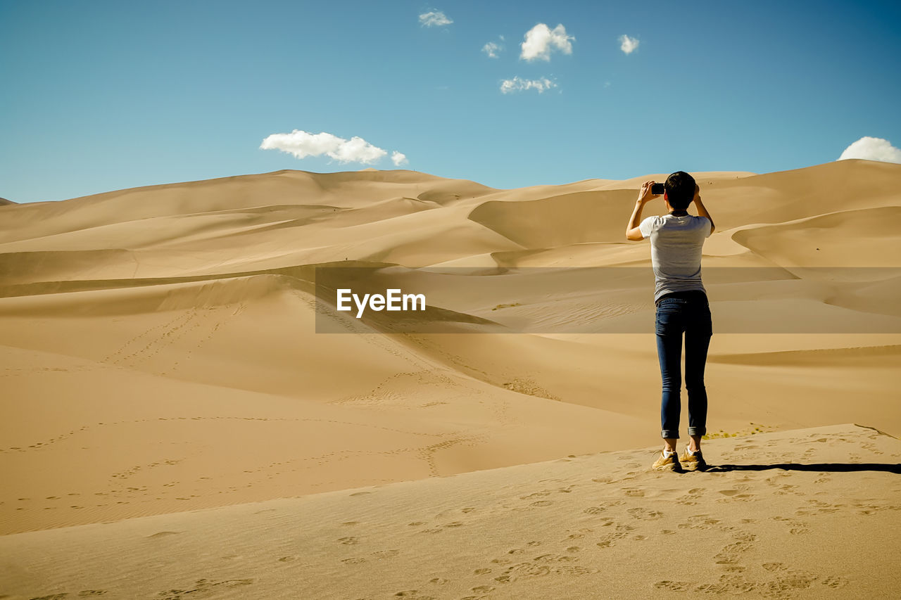 Rear view of young woman photographing desert