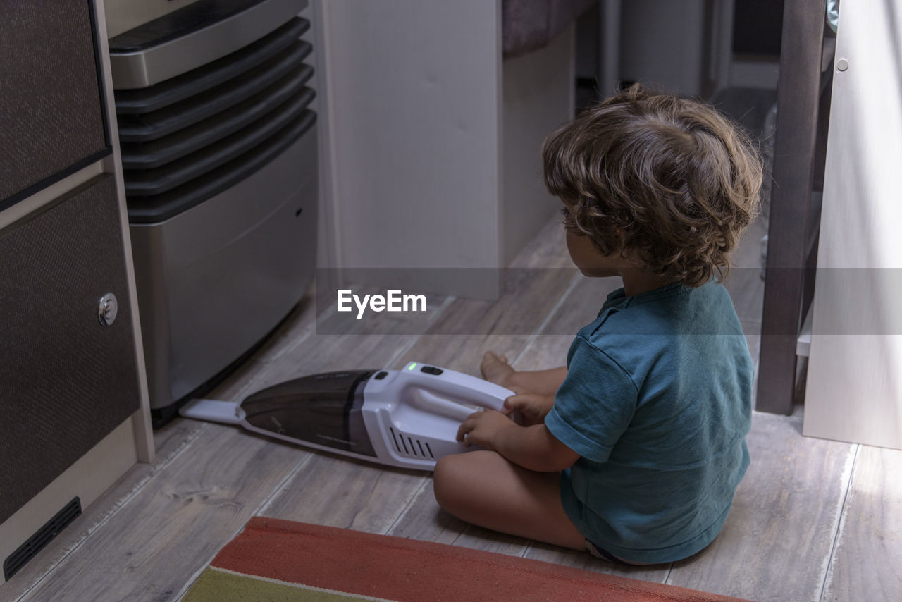 A sweet little boy vacuums the caravan while on vacation. a cute boy is cleaning the caravan.