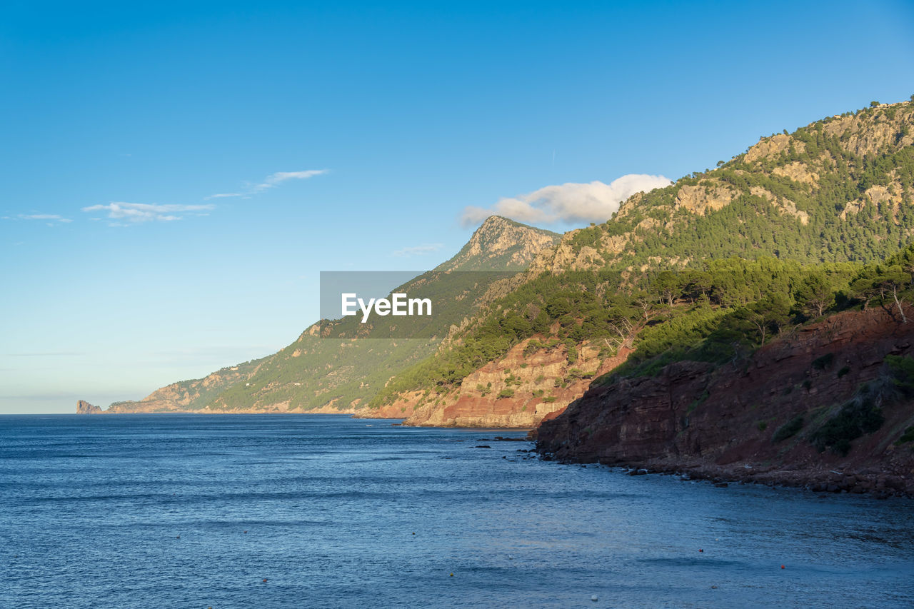 Scenic view of sea and mountains against blue sky