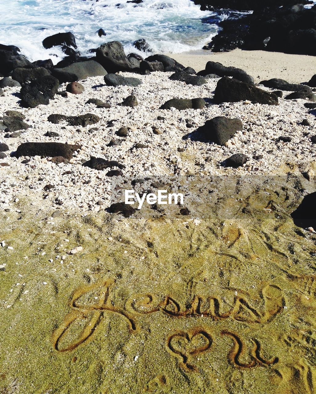 High angle view of text on sand at beach during sunny day