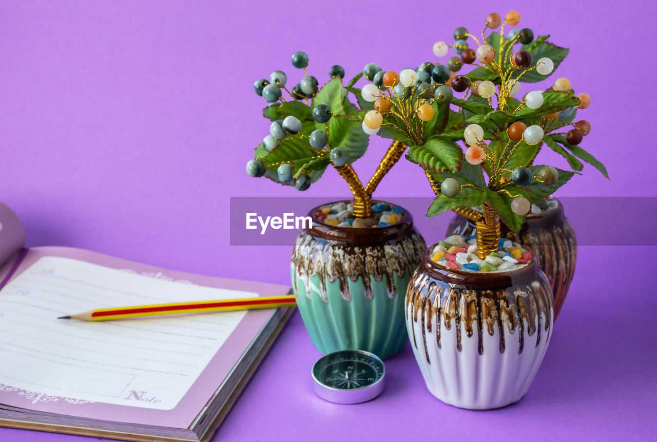 plant, purple, flower, flowering plant, table, indoors, no people, publication, book, nature, floristry, still life, vase, floral design, pen, studio shot, paper, art, freshness, food and drink, pencil, food, lilac, office supplies, potted plant, beauty in nature, pink, colored background