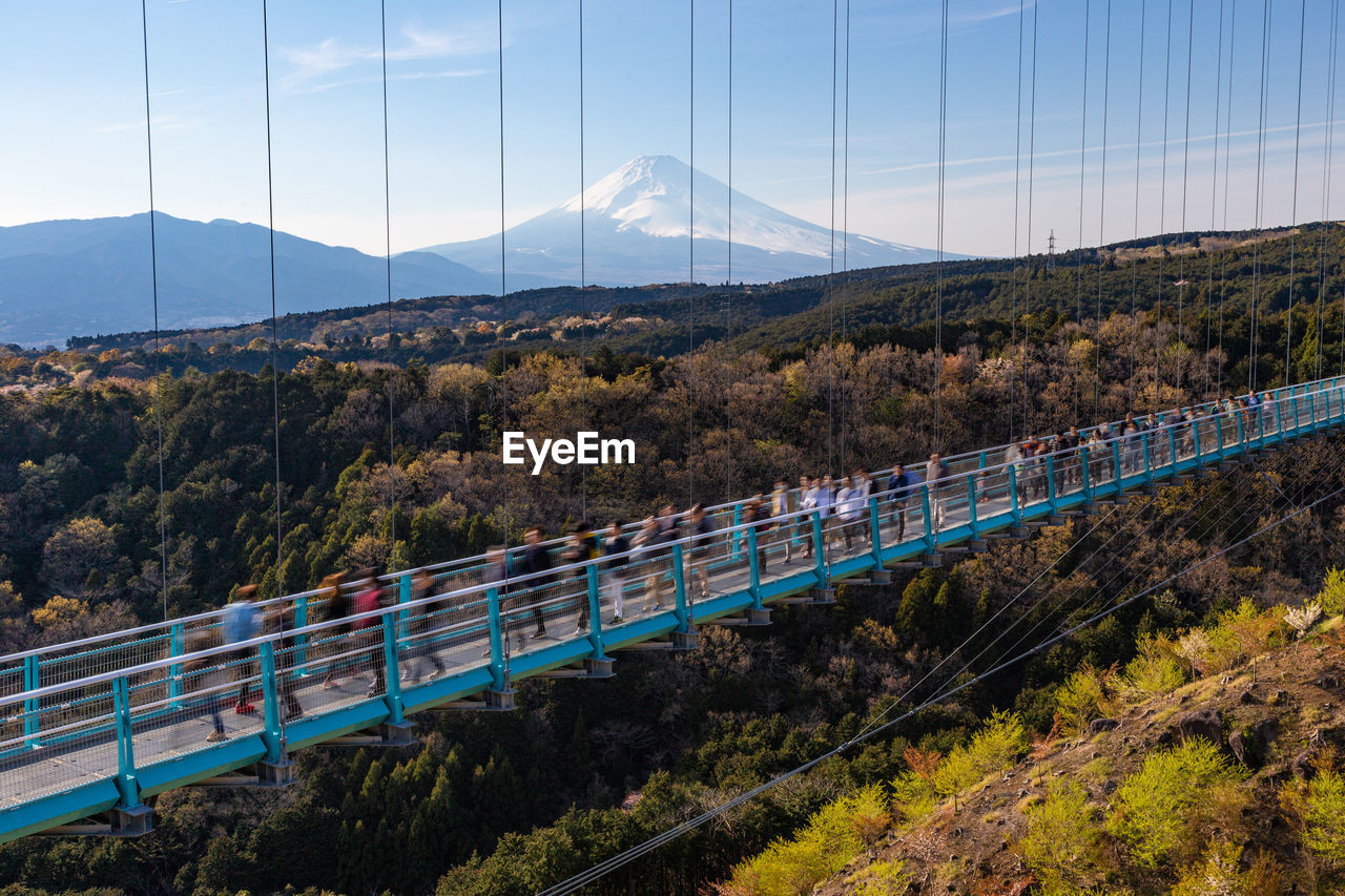 High angle view of people walking on footpath over forest against sky