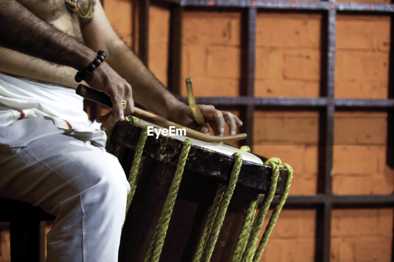Close-up of man playing drum in india during kathakali performance 
