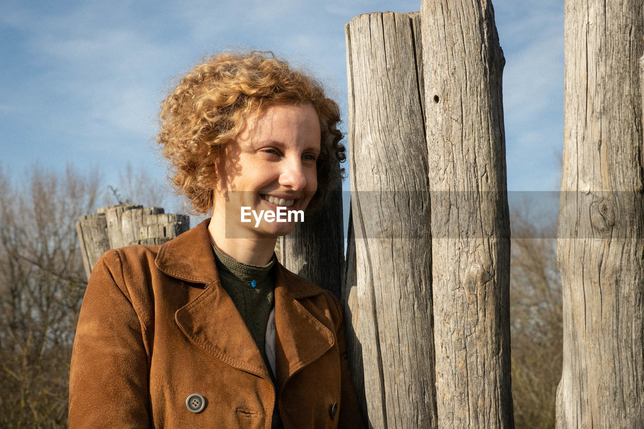 Smiling woman standing by fence