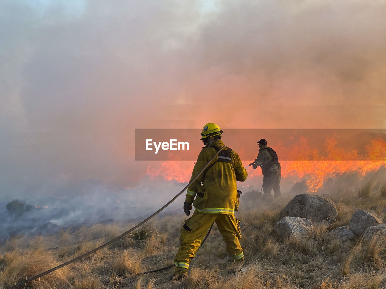 firefighter, fire, wildfire, burning, occupation, smoke, nature, flame, adult, accidents and disasters, men, warning sign, environment, headwear, mountain, clothing, protective workwear, sky, emergency services occupation, protection, sign, helmet, activity, heat, land, rescue worker, outdoors, fire hose, adventure, full length, communication, courage, landscape, backpack, forest fire, healthcare and medicine, person, working, security, fog, rear view, teamwork, cooperation, extinguishing, sports, risk, motion, emergency equipment, holding, two people