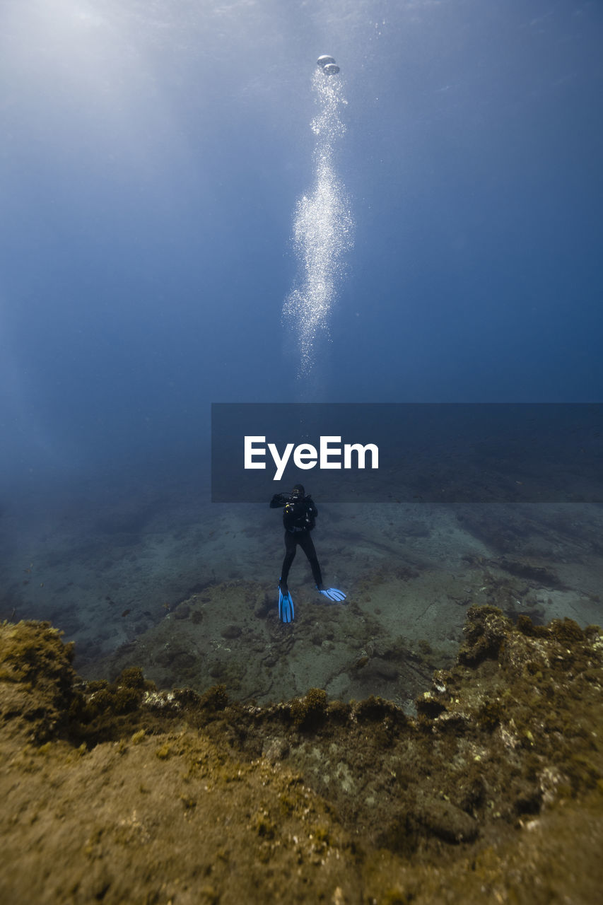 Woman scuba diving over ocean floor in blue sea