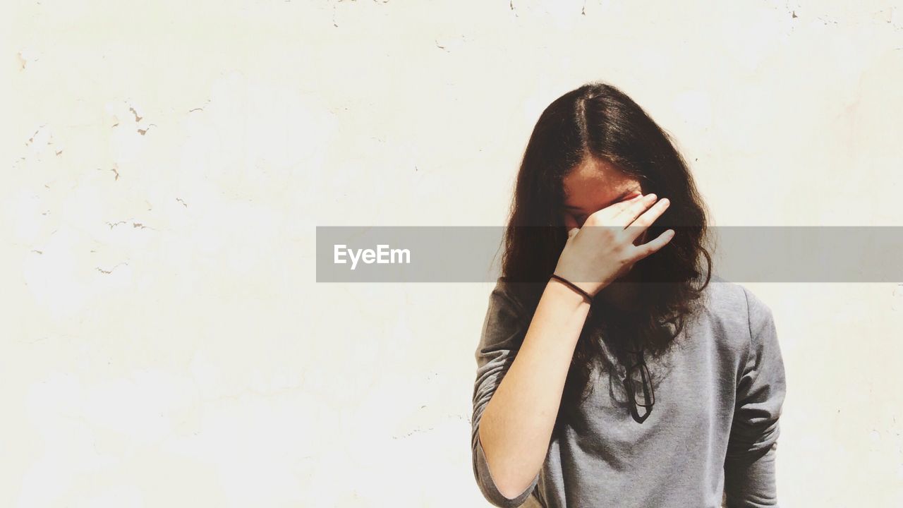Front view of displeased young woman against white wall