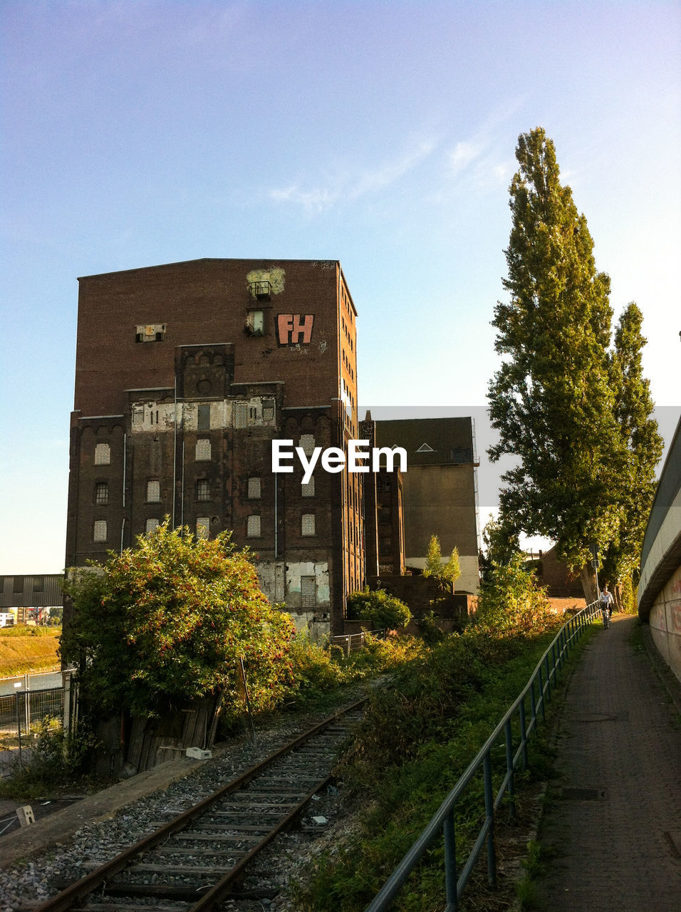 Trees and railway tracks by building against sky
