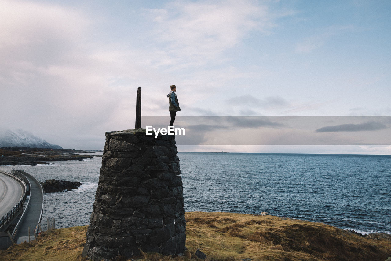 Rear view of man overlooking calm blue sea