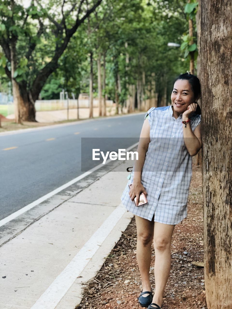 Full length of young woman using phone while standing on road