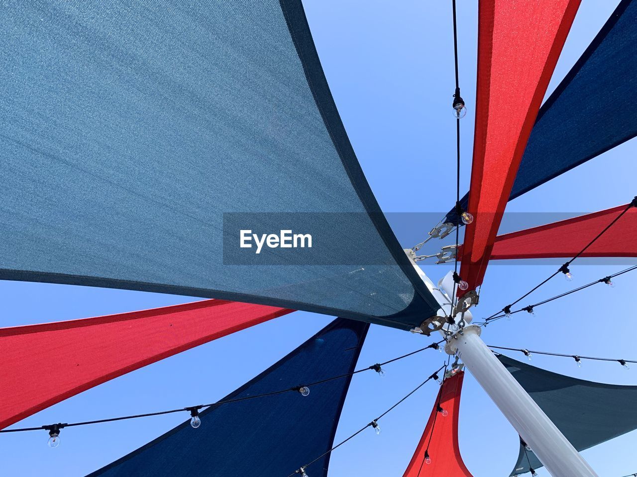 Low angle view of red and blue sun sail against clear sky