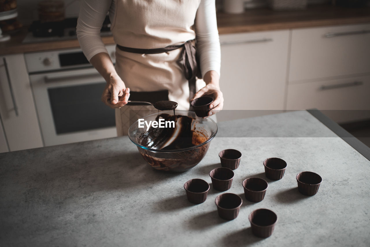 Woman making chocolate batter for muffins at home in kitchen closeup. selective focus. top view.