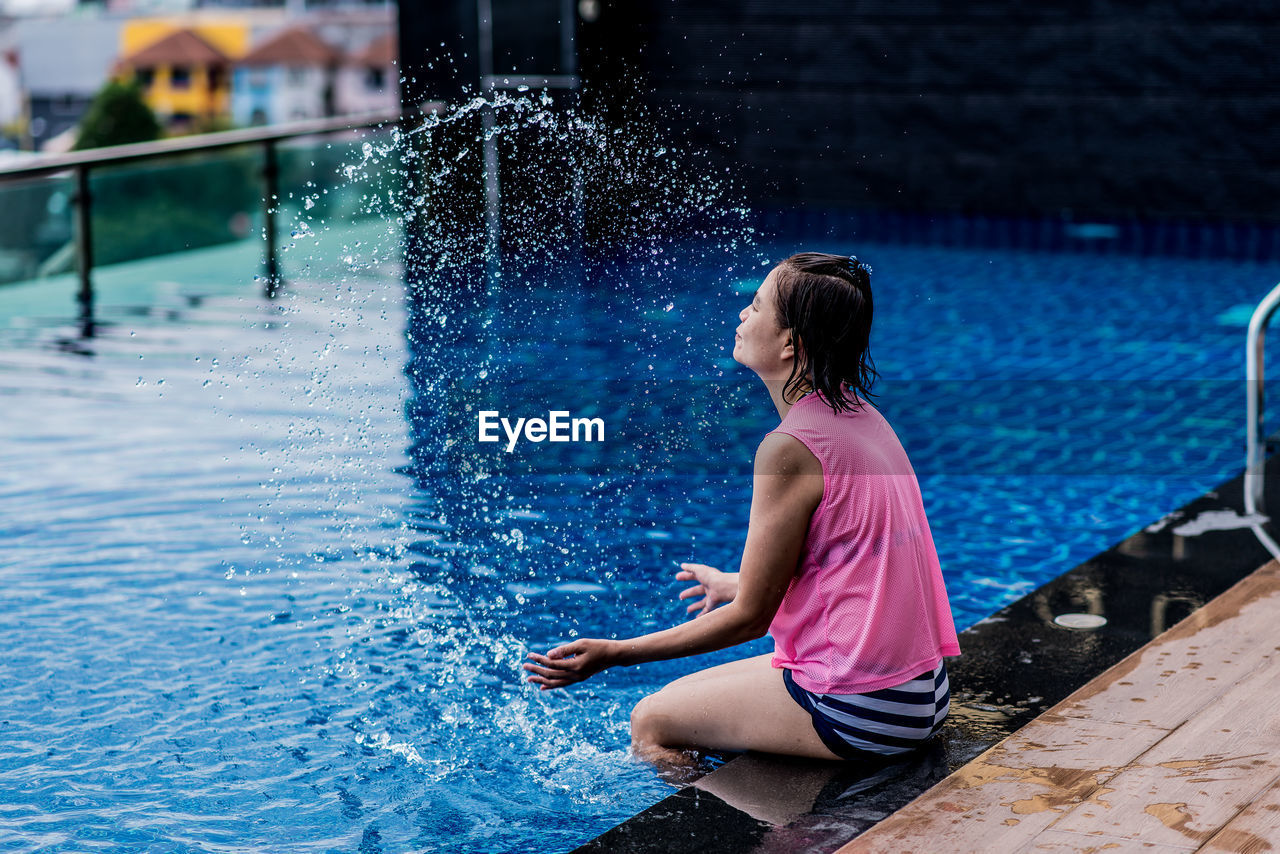 Woman sitting by swimming pool