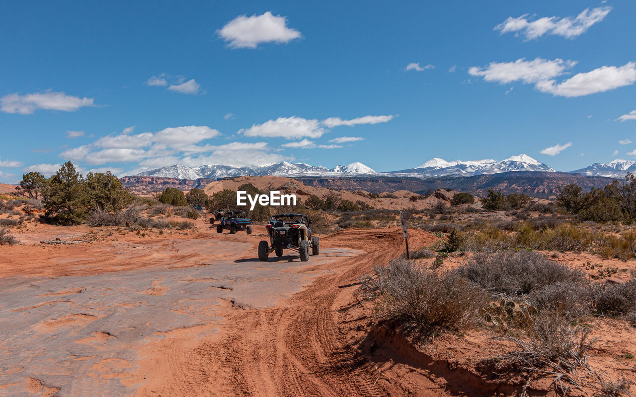 Full frame view of tourists enjoying a 4x4 tour in rugged terrain on a sunny day with mountains