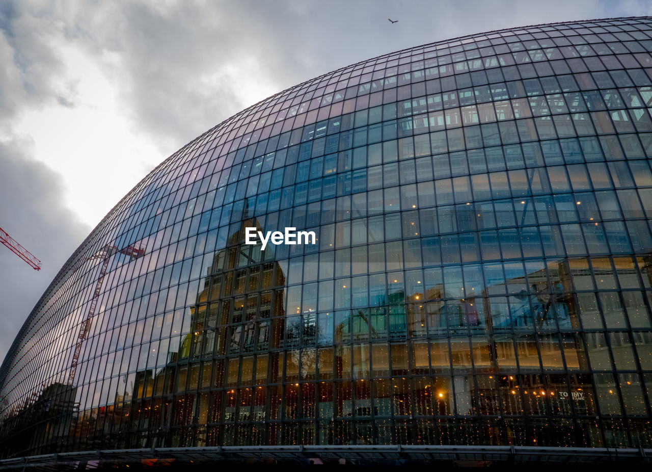 Low angle view of modern building against cloudy sky