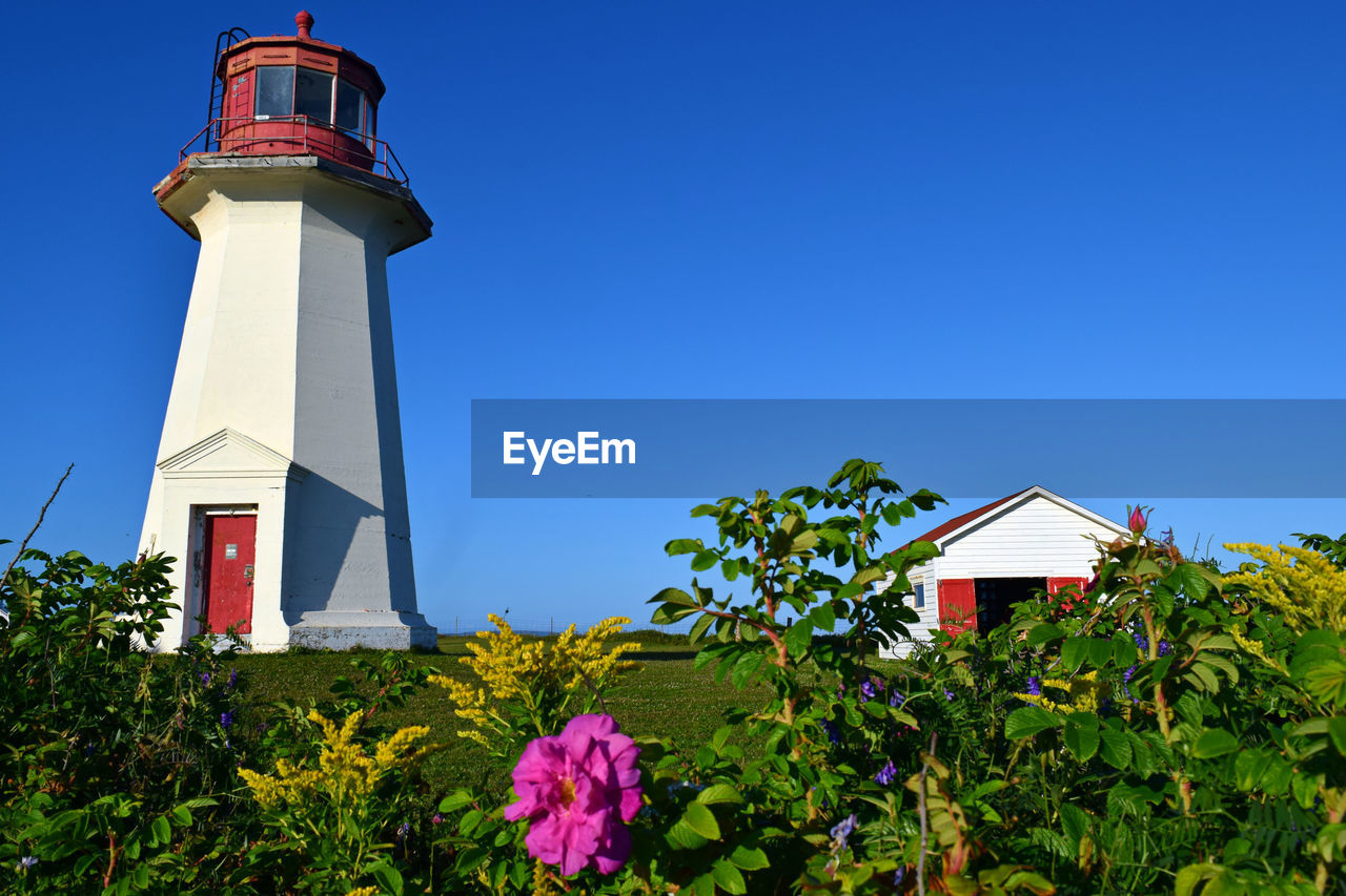 LOW ANGLE VIEW OF LIGHTHOUSE AMIDST BUILDINGS AGAINST SKY