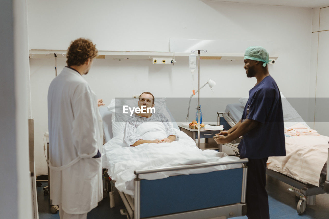 Male patient looking at doctor standing by nurse in hospital