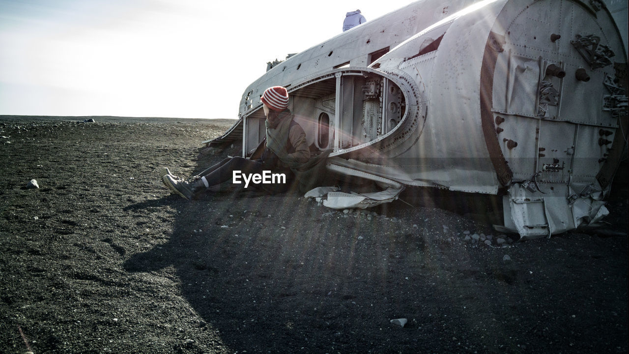 Woman sitting in front of airplane wreck