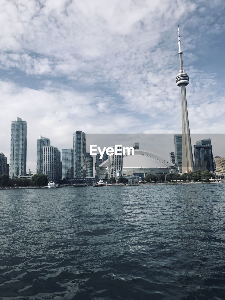 Sea and buildings in city against cloudy sky