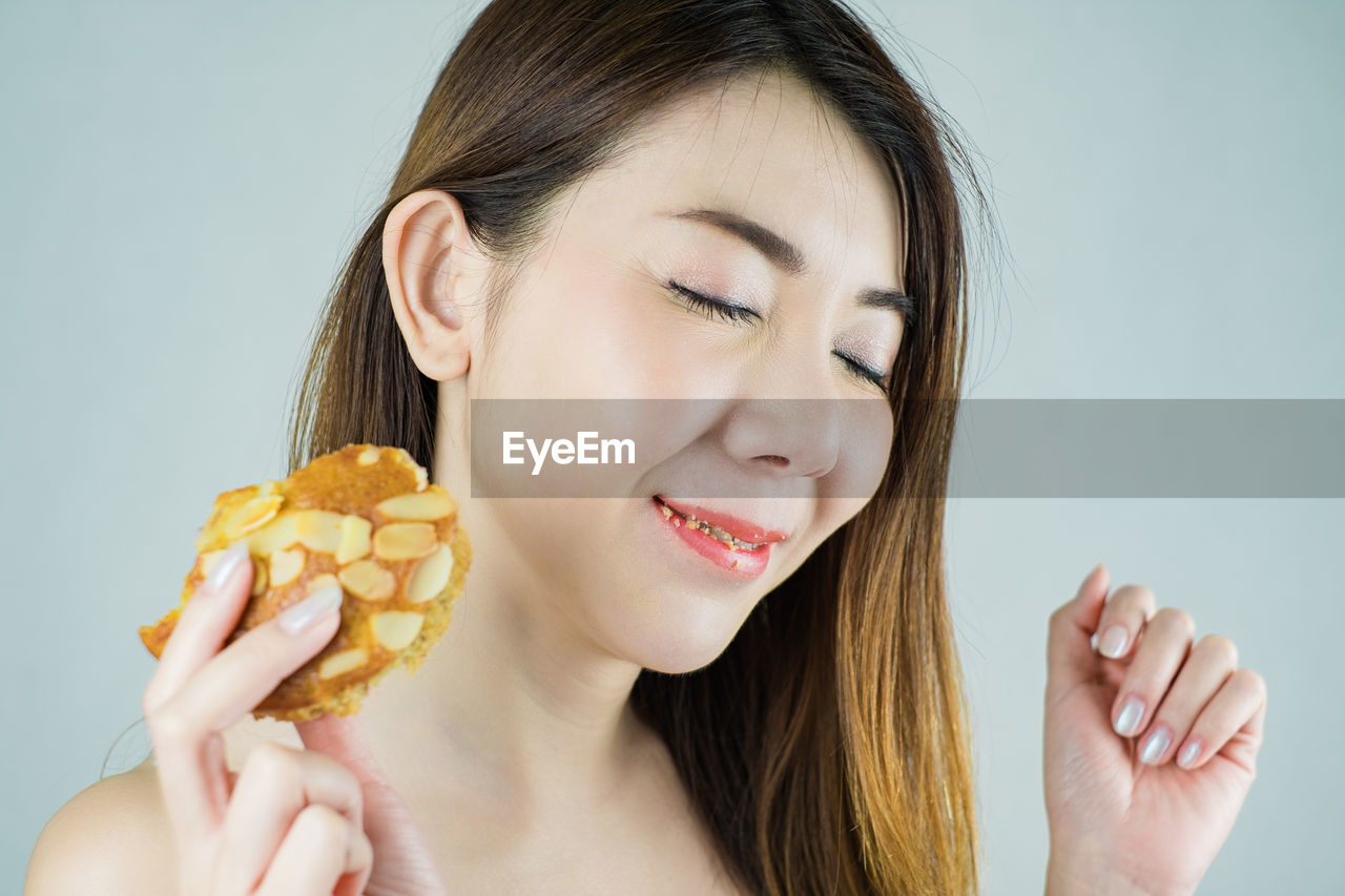 Close-up of woman having food against white background