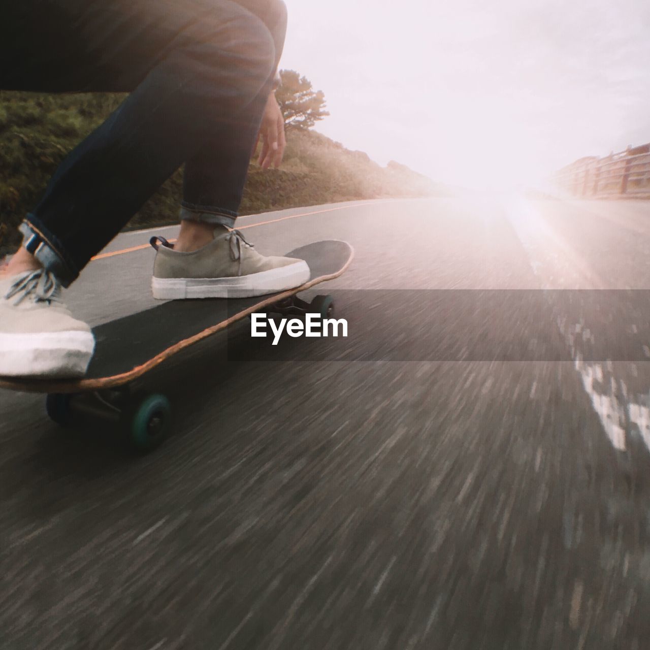 Low section of man skateboarding on road against sky