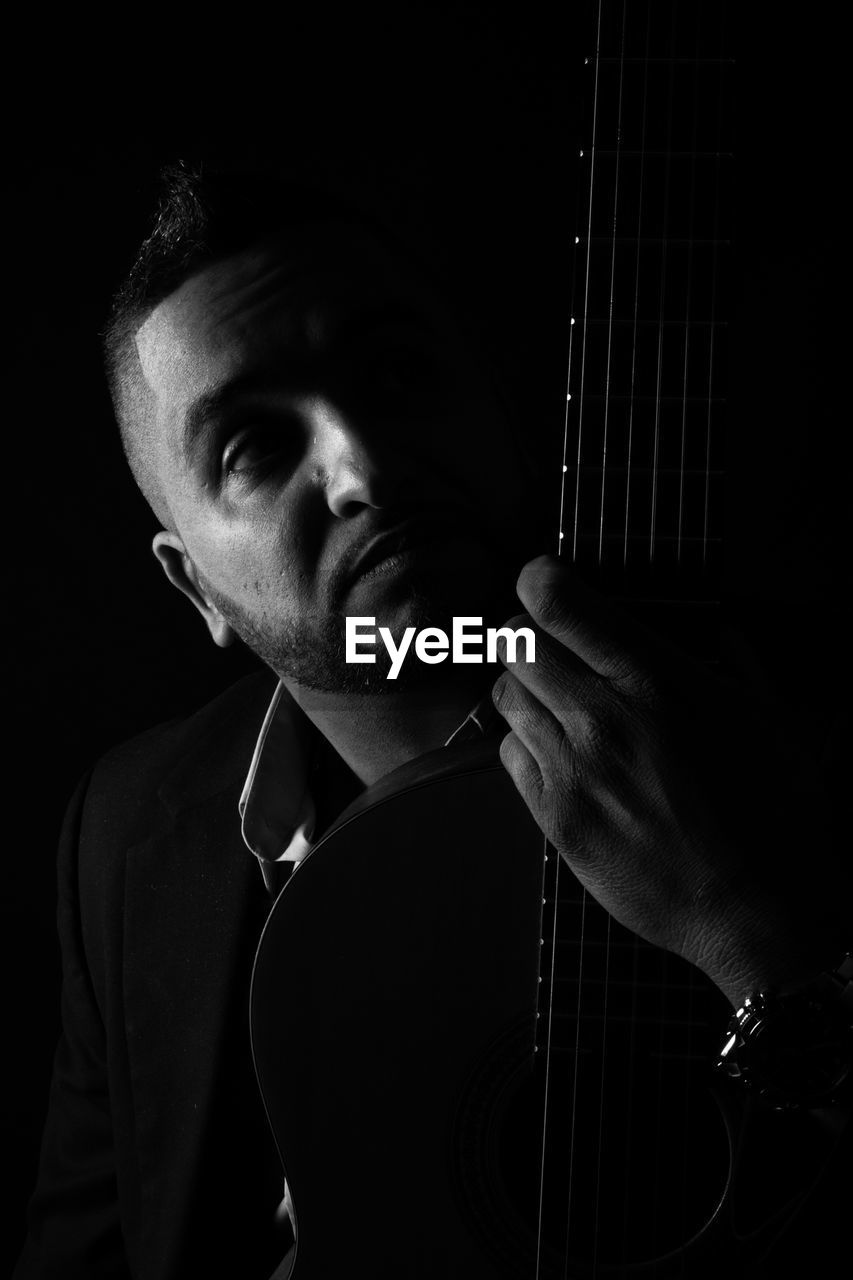 Man with guitar against black background