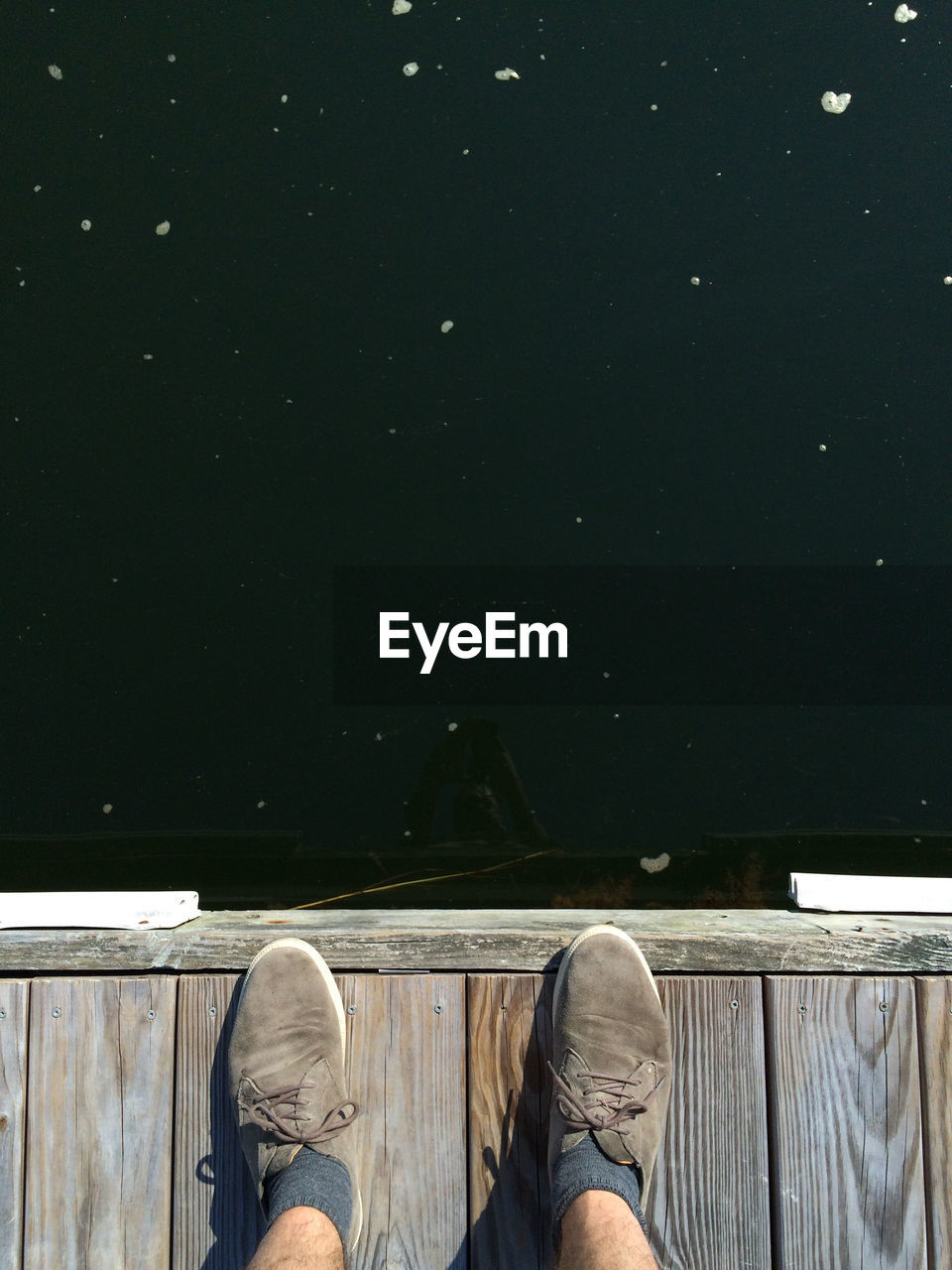 Low section of person standing on wooden pier