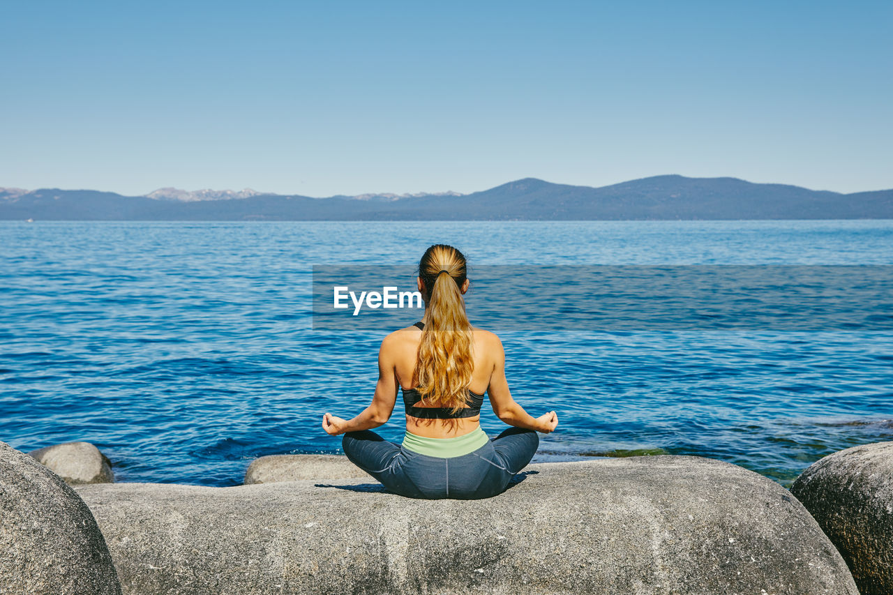 Young woman practicing yoga on lake tahoe in northern california.