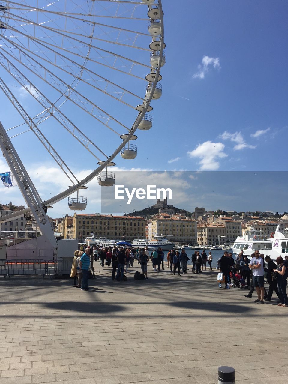 People at amusement park in city against sky