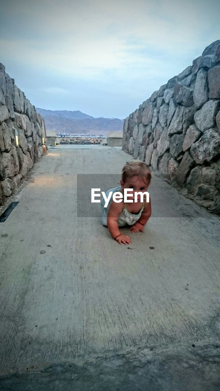 Portrait of toddler girl crawling at beach