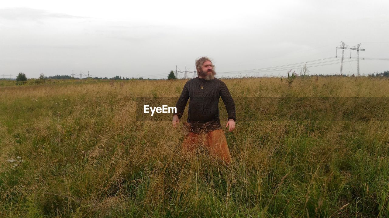 WOMAN STANDING ON FIELD AGAINST SKY