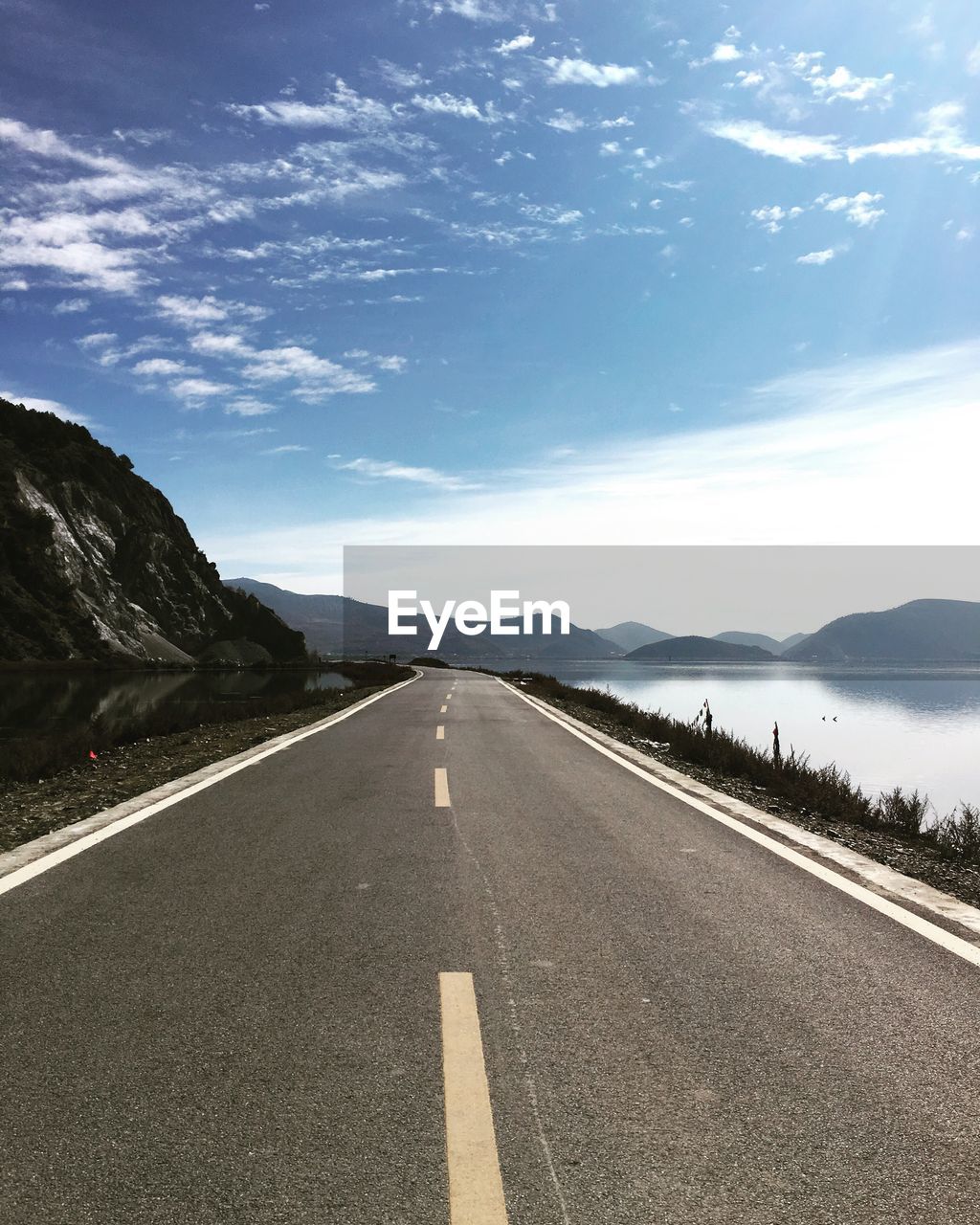 Empty road against cloudy sky