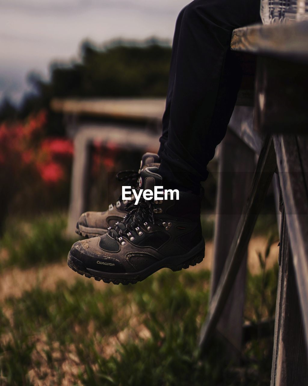 LOW SECTION OF MAN HOLDING CAMERA ON SHOES