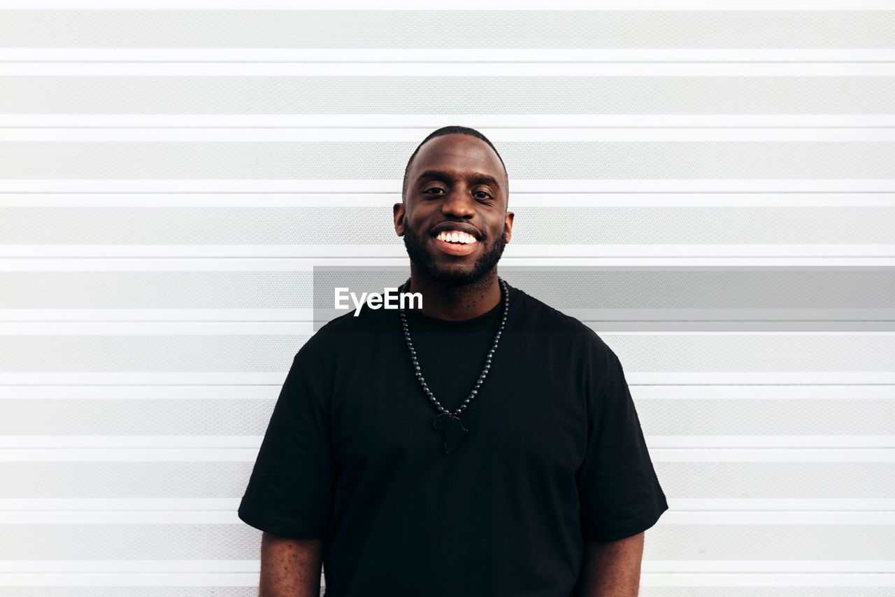 Happy black man posing and smiling over white background and looking at camera