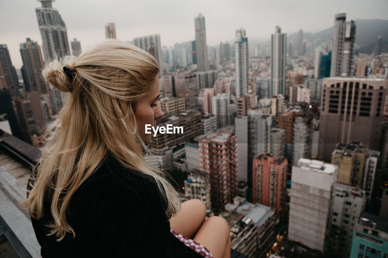 Woman sitting against cityscape