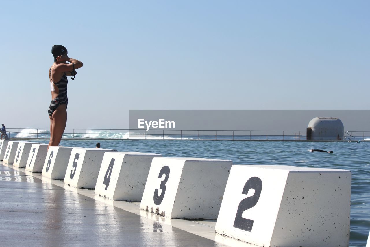 MAN LOOKING AT SEA AGAINST CLEAR BLUE SKY