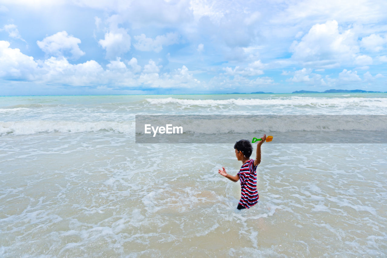 Full length of child on beach against sky