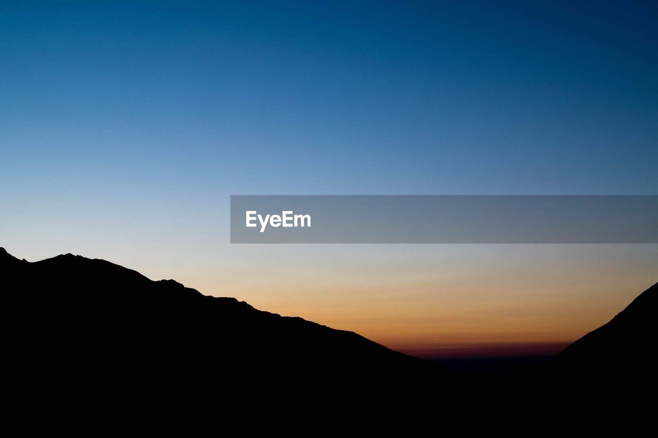 Silhouette mountains against clear blue sky