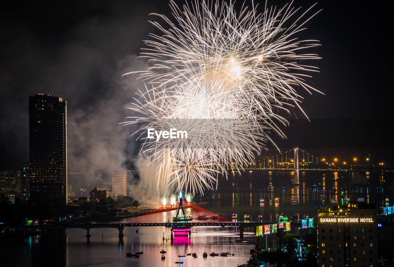 Firework display over river in city at night