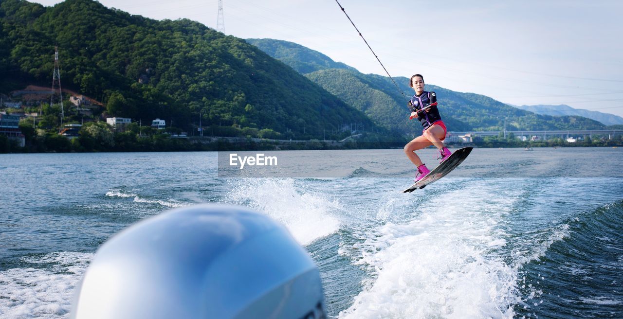 Full length of young woman wakeboarding on sea