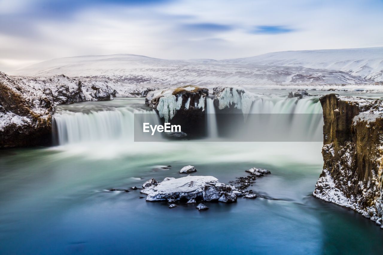 Scenic view of waterfall against sky during winter