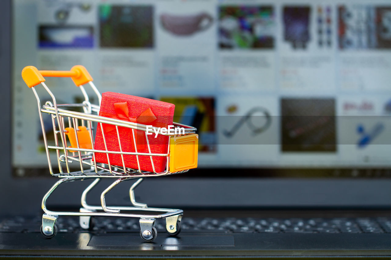Close-up of small shopping cart on laptop