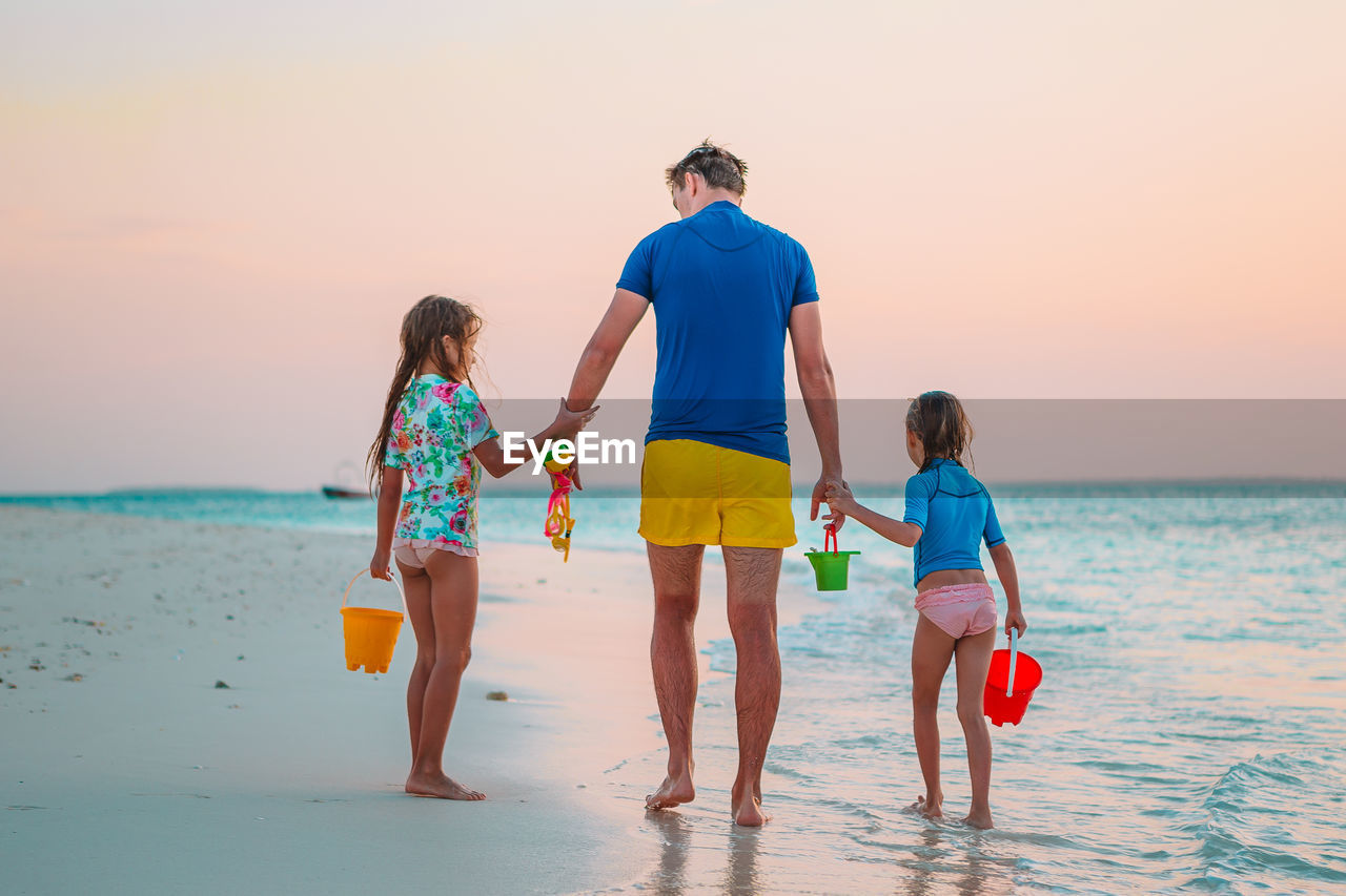 PEOPLE ON BEACH AGAINST SKY DURING SUNSET